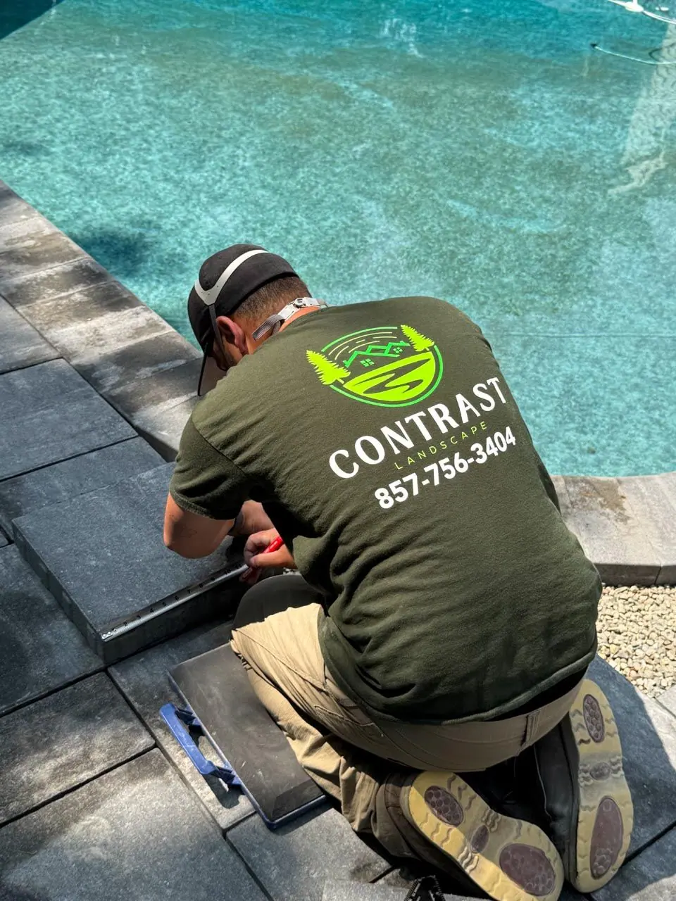 Contrast Landscape crew member setting pool coping on a paver patio