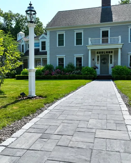 Paver walkway with a lamp post leading to a colonial home