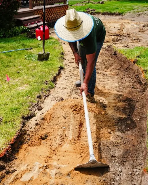 Crew member trenching soil for a new walkway